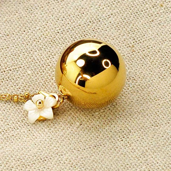 bola de grossesse de couleur or avec en pendentif une fleur blanche